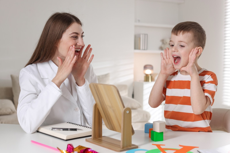 An SLP doing speech therapy with a young boy