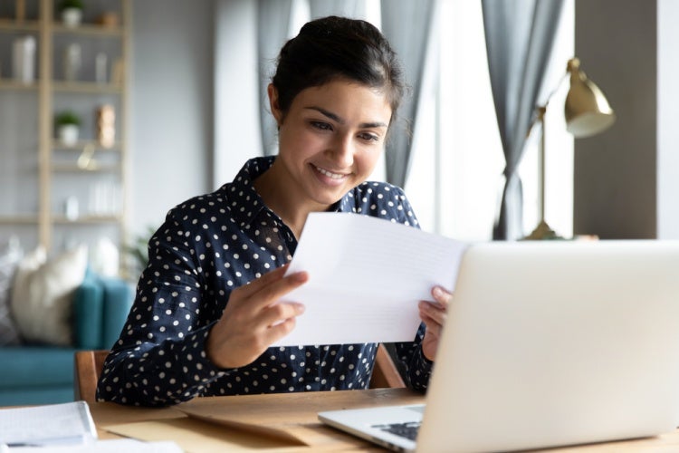 Ethnic female business professional holding up a paper and smiling