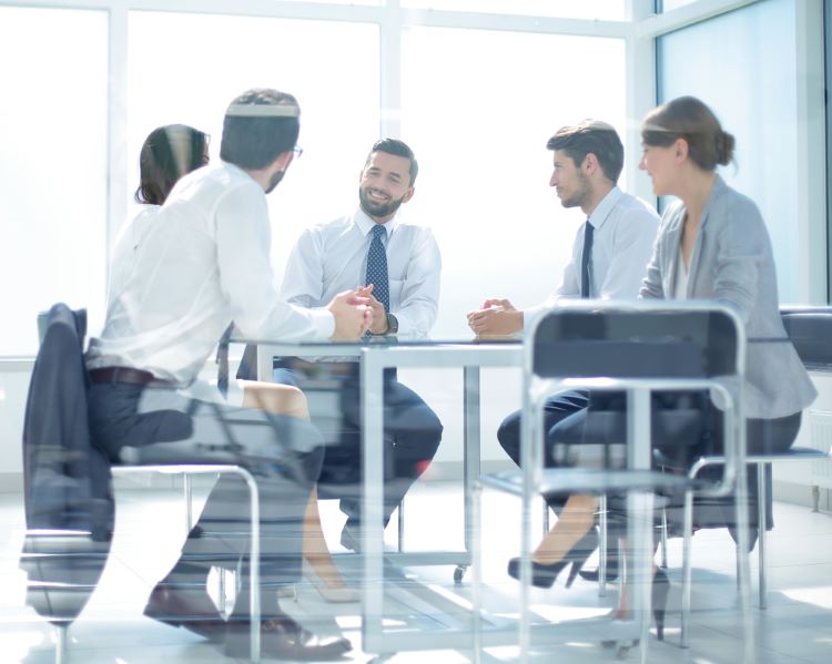 Group of business professionals holding a meeting in a modern glass boardroom