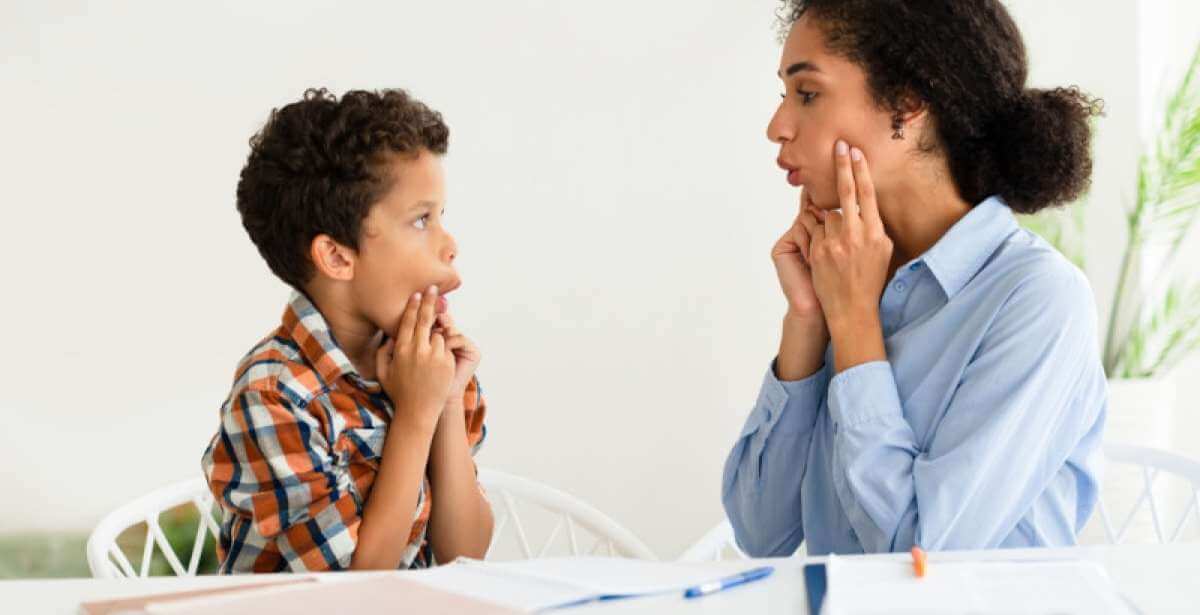 An SLP working with a young client to form proper mouth sounds
