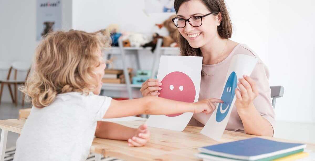 Speech Language Pathologist holding up signs for a child