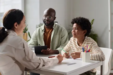 A smiling young boy talking to a friendly social worker at a desk in the office