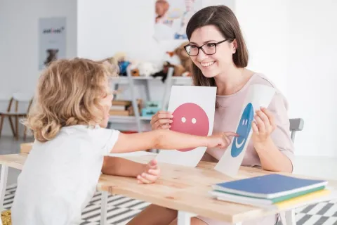 Speech Language Pathologist holding up signs for a child