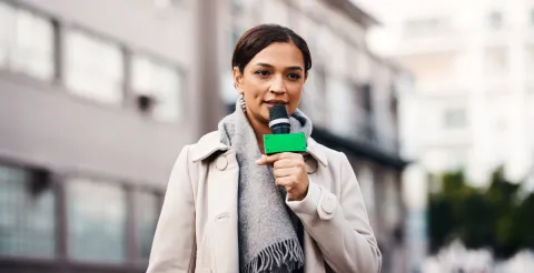 A correspondent speaks into a digital microphone.